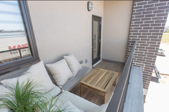 A balcony with a couch and pillows.