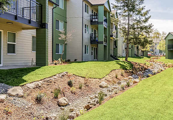 A row of apartment buildings with a landscaped garden in front.