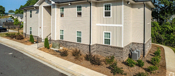an apartment building with tan siding and a gray roof