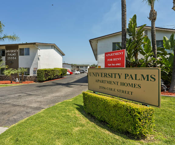 a sign for the university palms apartment homes on the side of a road