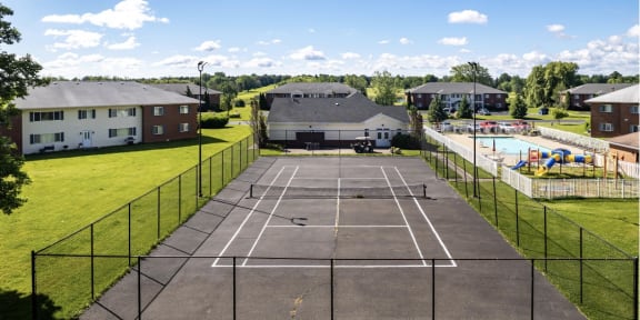 an aerial view of a tennis court with a pool in the background