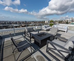 a rooftop patio with a table and chairs and a fire pit