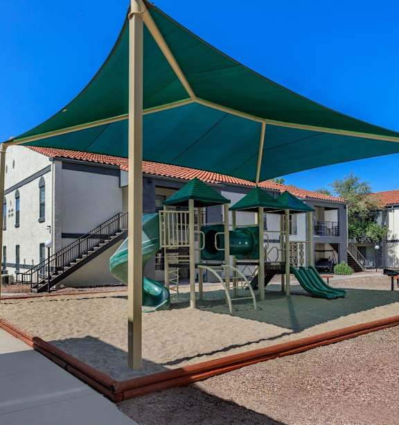 A playground with a green canopy and a slide.