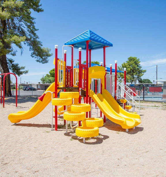 A playground with a yellow slide and red and yellow climbing structures.