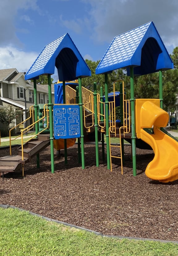 a playground with a yellow slide and a blue and yellow climbing structure