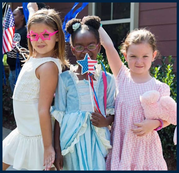 Three children are standing together, one holding a star-shaped object.