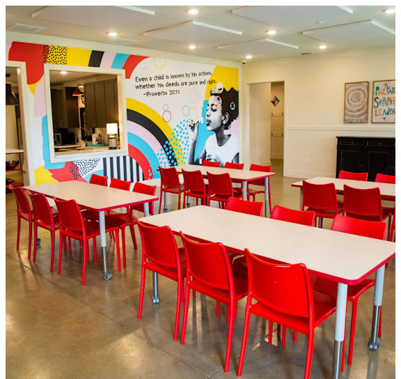 A room with tables and chairs and a Proverbs 2011 quote on the wall.
