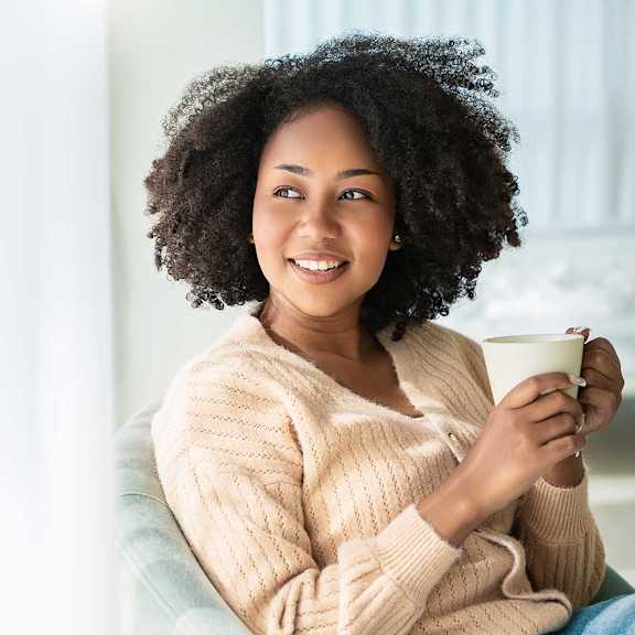 A woman with curly hair is holding a cup.