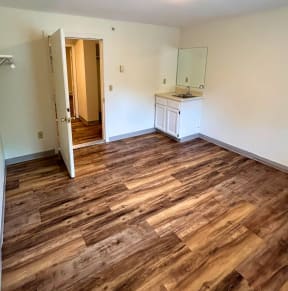 an empty living room with a kitchen in the background
