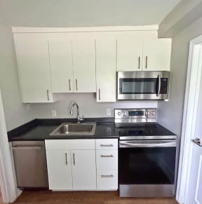 a small kitchen with white cabinets and black countertops