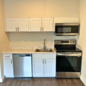 a small kitchen with white cabinets and stainless steel appliances