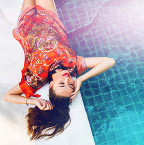 a woman in a red dress laying on the side of a pool