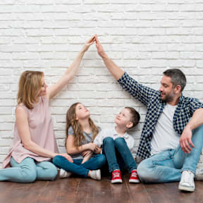 a happy family sitting against a wall with their hands together