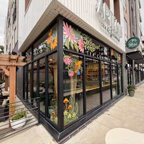 A storefront with a glass window and a wooden bench in front.