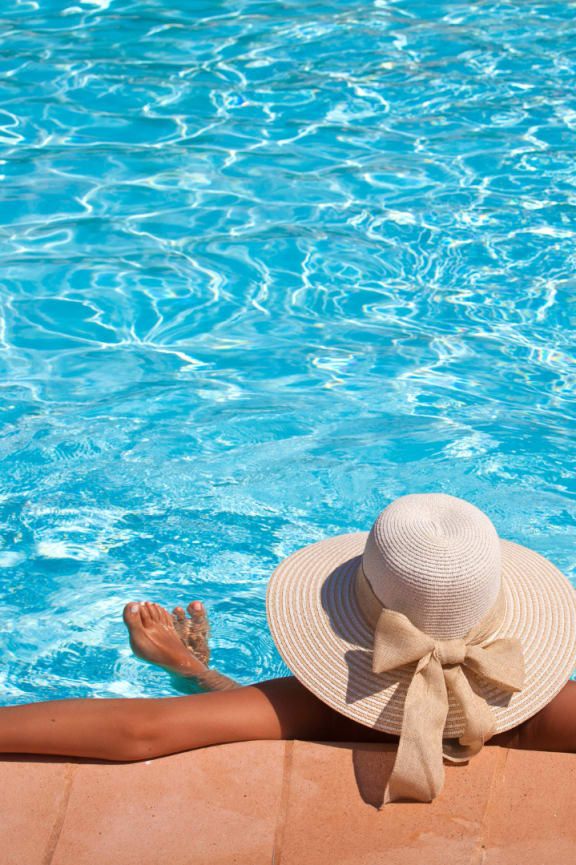 a woman laying in a pool with a hat on