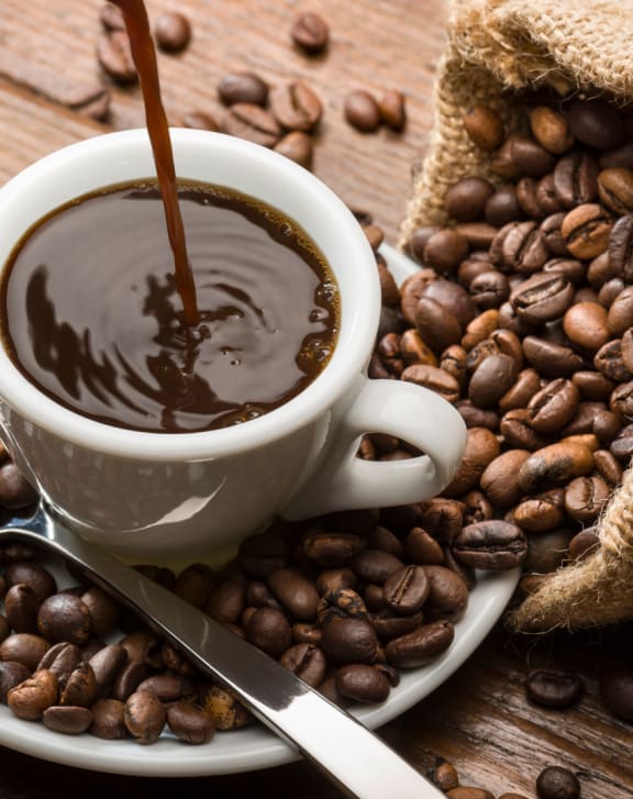 coffee pouring into a cup of coffee beans