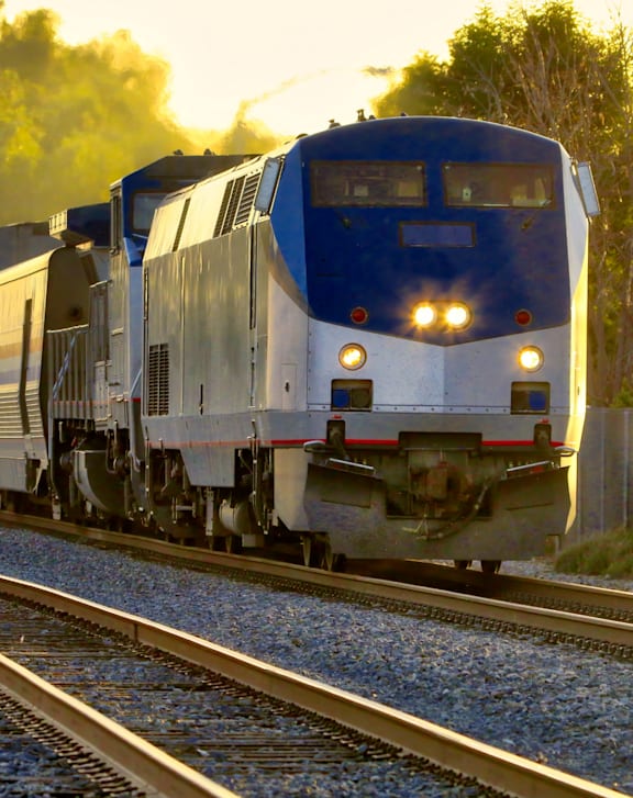 A blue and silver train is on the tracks.