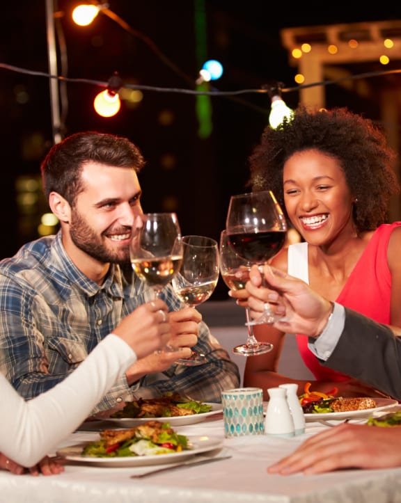 a group of people eating and drinking wine at a restaurant