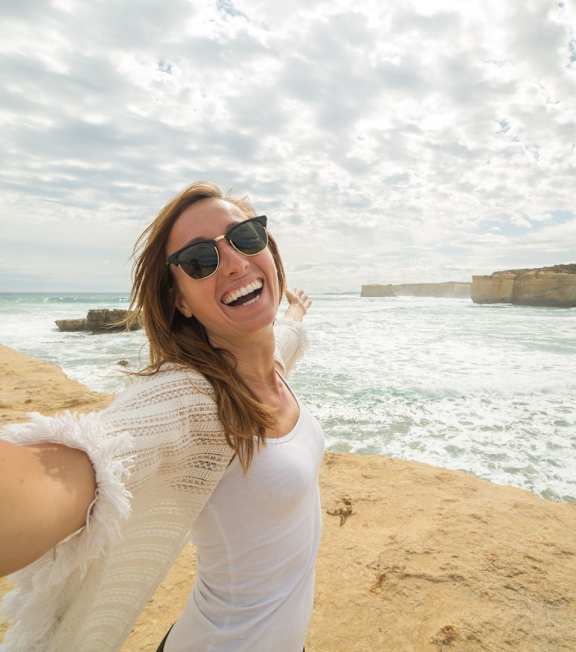 A woman is taking a selfie at the beach.