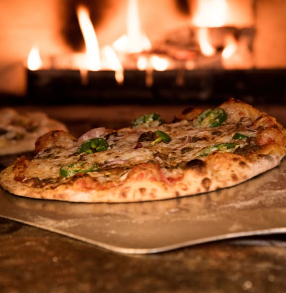 a pizza sitting on a pan in front of a fireplace