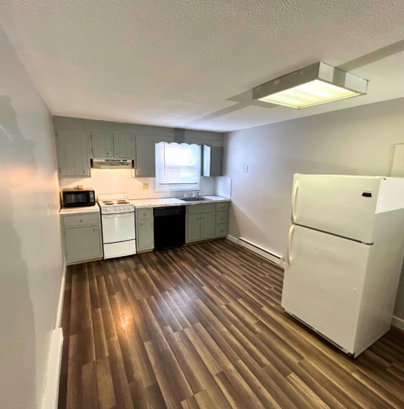 a kitchen with white appliances and a wooden floor