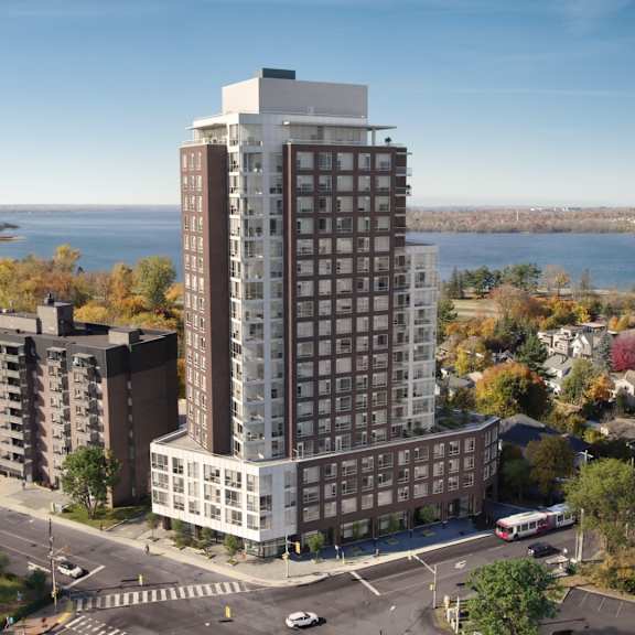 A modern apartment building with balconies is surrounded by trees and people are walking around in the foreground.