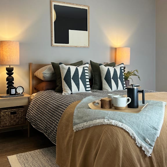 A bed with a grey and white checkered comforter and a blue blanket on top.