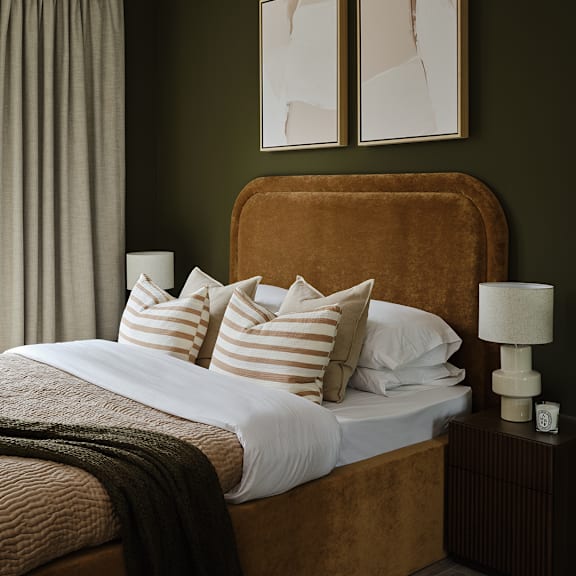 A bedroom with a bed, pillows, a blanket, a nightstand, and a ceiling fan.