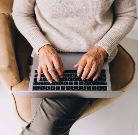a person sitting on a chair using a laptop computer