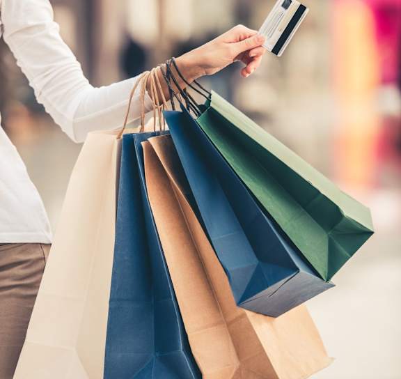 A person holding a credit card and shopping bags.