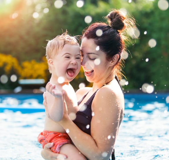 a woman holding a baby in a swimming pool