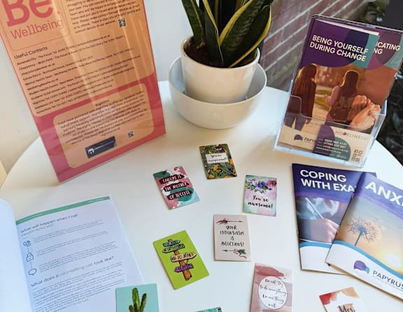 A table with a booklet titled "Be Wellbeing" and other self-help books and cards.