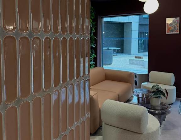A room with a brown wall and a glass table with a plant on it.