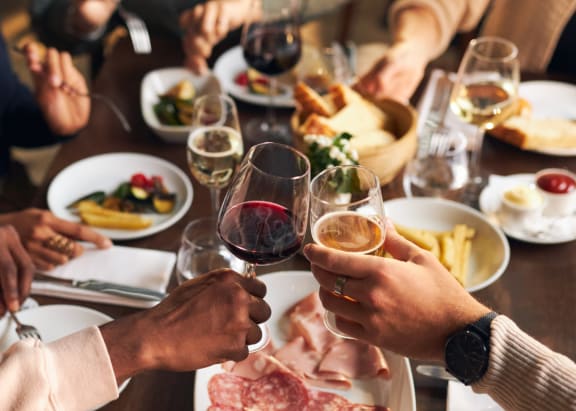 a group of people sitting around a dinner table drinking wine