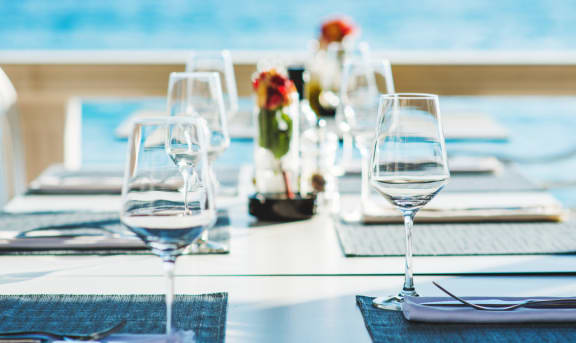a table set for a meal with a view of the ocean in the background