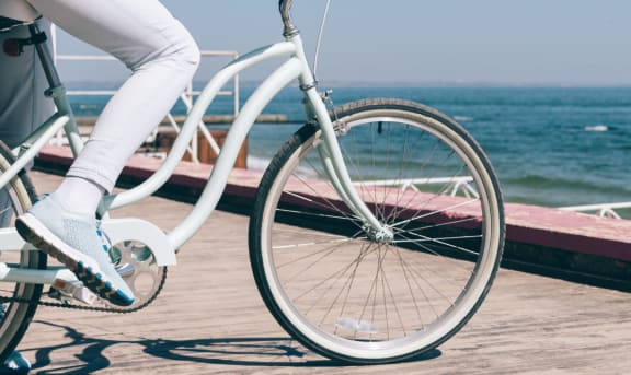 a woman riding a bike on a boardwalk with the ocean in the background