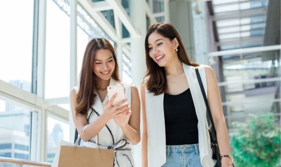 two young women with shopping bags and cell phone in the mall premium photo