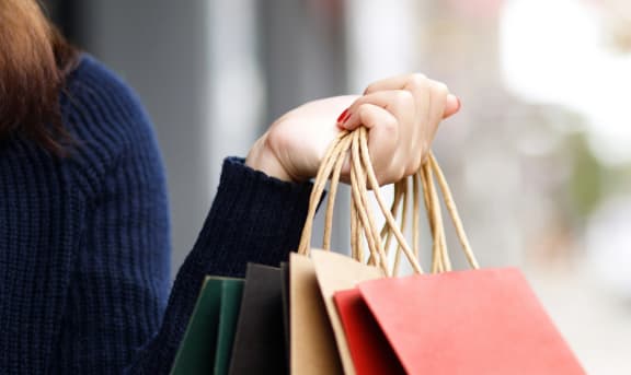 a woman holding a bunch of shopping bags in her hand