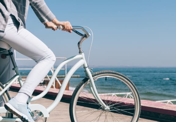 a woman riding a bike on a boardwalk near the ocean