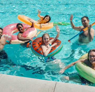 a group of people swimming in a pool with rafts