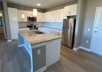 A kitchen with a granite countertop and stainless steel refrigerator.