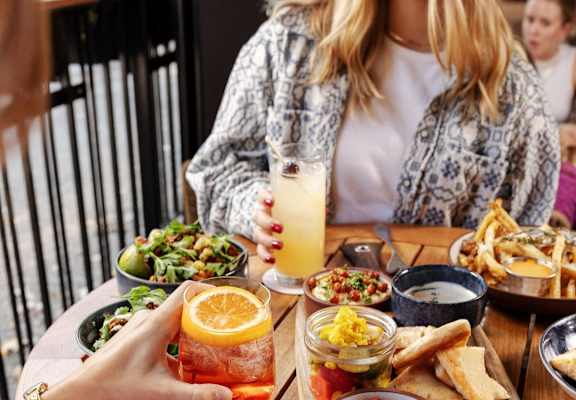 A woman is sitting at a table with a variety of food and drinks at Bradford Gwinnett Apartments and Townhomes in Norcross, GA, 30071
