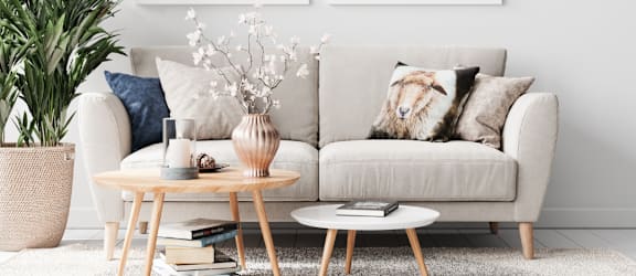 a living room with a couch and two coffee tables in front of a white wall with two