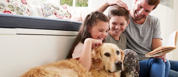 a family sitting on the floor with their dog
