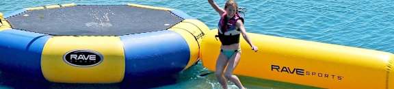 two women jumping on an inflatable trampoline in the water