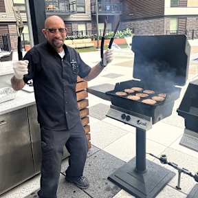 A man grilling hamburgers on a Weber grill.