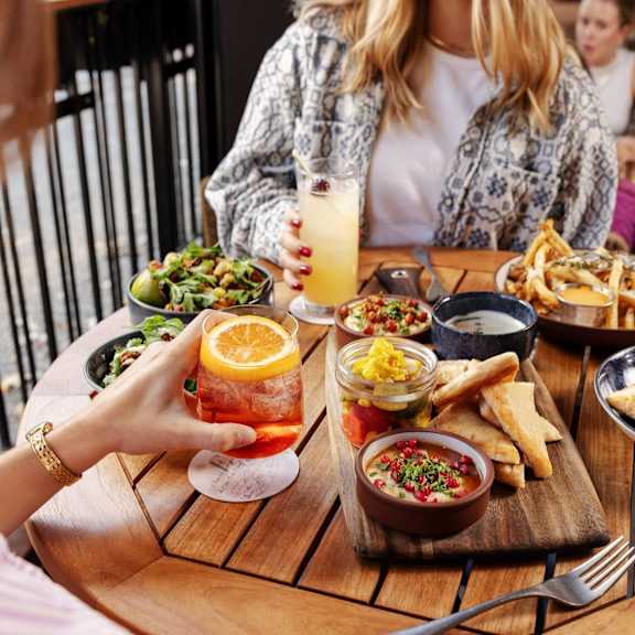 A food truck with a woman ordering food and two men standing nearby.