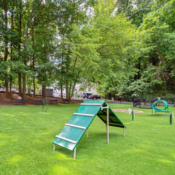 a green metal slide in a park with trees at Lake Johnson Mews, Raleigh, 27606