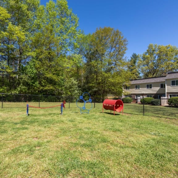 a playground with a red barrel and two blue hoops in the grass