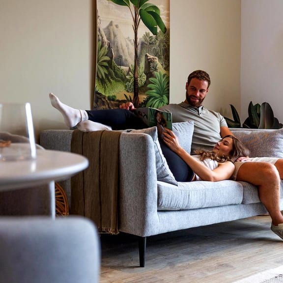 a man and a woman sitting on a couch with a tablet